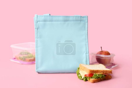 Téléchargez les photos : Sac, boîtes à lunch avec de délicieux plats et sandwich sur une table en bois rose près du mur - en image libre de droit