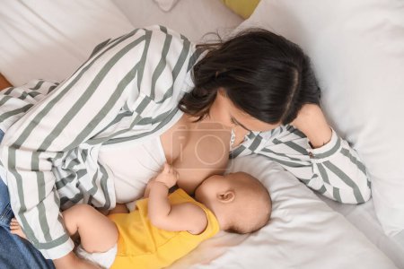 Photo for Young woman breastfeeding her baby in bedroom - Royalty Free Image