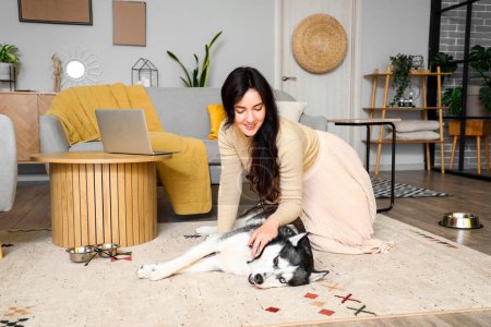 Foto de Mujer joven con lindo perro Husky en casa - Imagen libre de derechos