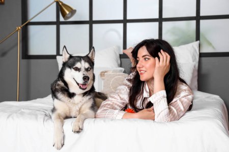 Foto de Mujer joven con su perro Husky en el dormitorio - Imagen libre de derechos