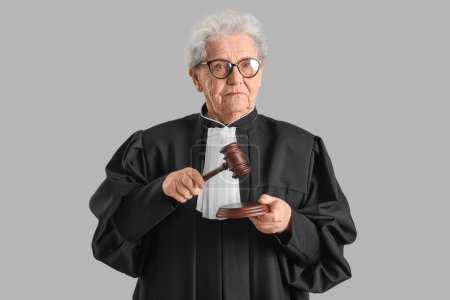 Photo for Senior judge with gavel on grey background - Royalty Free Image
