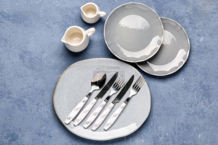 Photo for Clean plates, pitchers and set of cutlery on grey grunge table - Royalty Free Image
