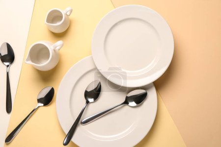 Photo for Clean plates, set of spoons and pitchers on beige background - Royalty Free Image