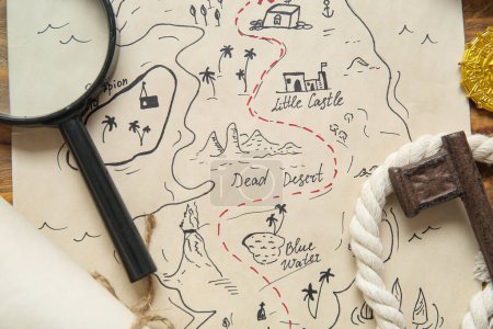 Treasure map with magnifier and key on brown wooden background