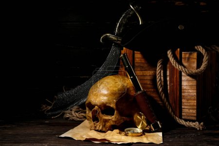 Chest with human skull, sword, spyglass and compass on brown wooden background