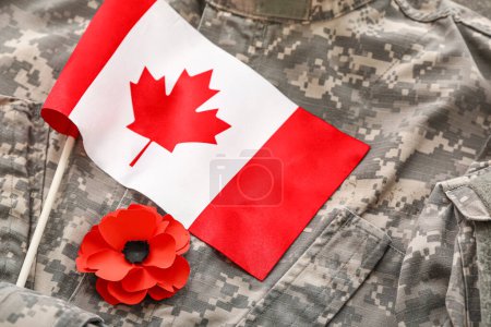 Foto de Flor de amapola y bandera de Canadá en uniforme militar, primer plano. Día del Recuerdo - Imagen libre de derechos
