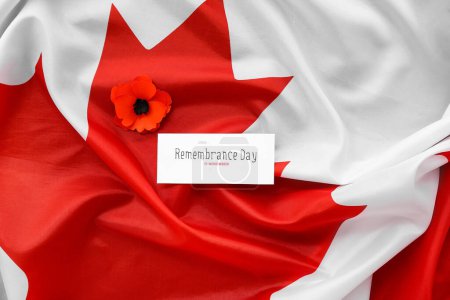 Foto de Flor de amapola y tarjeta en la bandera de Canadá como fondo. Día del Recuerdo - Imagen libre de derechos
