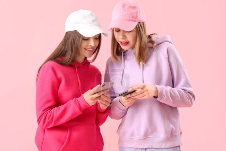 Foto de Amigos femeninos usando teléfonos móviles sobre fondo rosa - Imagen libre de derechos