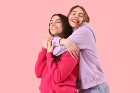 Foto de Amigas abrazándose sobre fondo rosa - Imagen libre de derechos