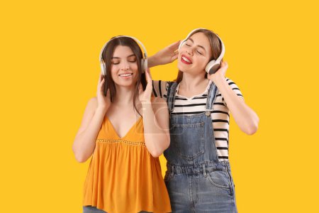 Foto de Amigos femeninos en auriculares sobre fondo amarillo - Imagen libre de derechos