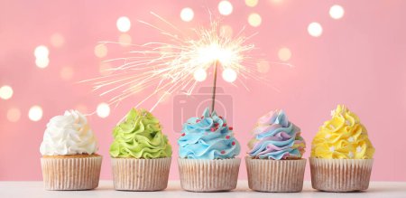 Photo for Tasty cupcakes with sparkler on pink background - Royalty Free Image