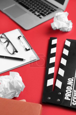 Photo for Clipboard with crumpled paper and movie clapper on red background, closeup - Royalty Free Image