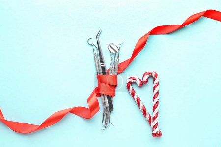 Photo for Dental tools with red ribbon and candy canes on blue background - Royalty Free Image