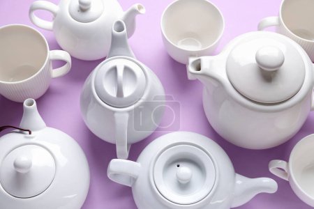 Foto de Muchas teteras de porcelana y tazas sobre fondo lila - Imagen libre de derechos
