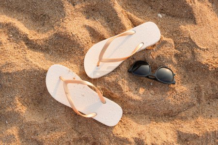 Foto de Chanclas con estilo con gafas de sol en la arena en el resort - Imagen libre de derechos