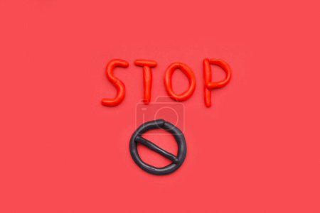 Photo for Red word STOP with sign made of play dough on red background - Royalty Free Image