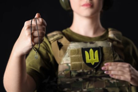 Foto de Joven soldado femenino con colgante tridente ucraniano sobre fondo oscuro, primer plano - Imagen libre de derechos