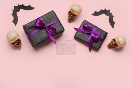 Komposition mit Geschenkschachteln und Halloween-Dekorationen auf rosa Hintergrund