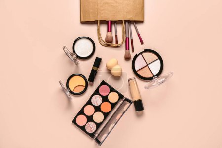 Foto de Bolsa de compras con cosméticos de maquillaje sobre fondo beige - Imagen libre de derechos