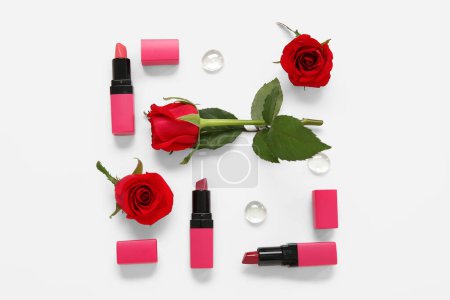 Téléchargez les photos : Composition avec différents rouges à lèvres de maquillage et de belles fleurs roses rouges sur fond blanc - en image libre de droit