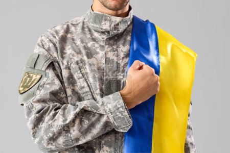 Photo for Male soldier with Ukrainian flag on grey background - Royalty Free Image