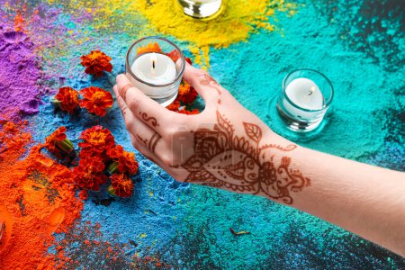 Photo for Female hand with colorful powder, candles and marigold flowers for celebration of Divaly on dark background - Royalty Free Image