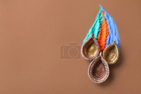 Photo for Diya lamps with colorful powder for celebration of Divaly on brown background - Royalty Free Image