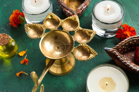 Photo for Diya lamps with candles, aroma oil and marigold flowers on grunge green background. Divaly celebration - Royalty Free Image