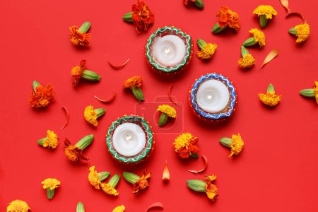 Téléchargez les photos : Bougies brûlantes avec des fleurs de souci sur fond rouge. Célébration divine - en image libre de droit