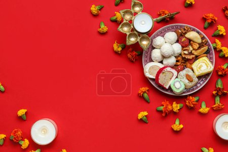 Photo for Burning candles with diya lamps, marigold flowers and plate of treats on red background. Divaly celebration - Royalty Free Image