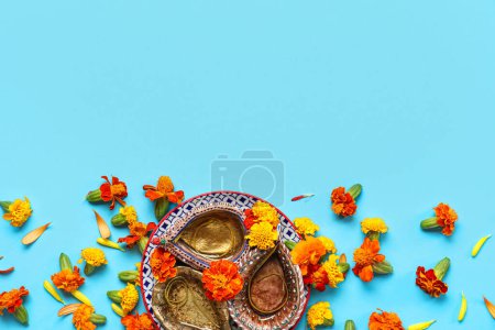 Photo for Diya lamps with marigold flowers on blue background. Divaly celebration - Royalty Free Image
