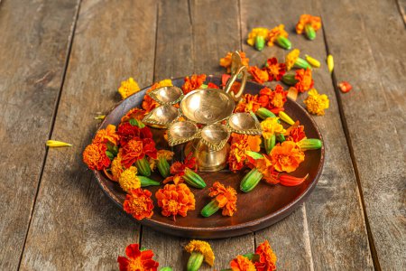 Photo for Plate with diya lamp and marigold flowers on brown wooden background. Divaly celebration - Royalty Free Image