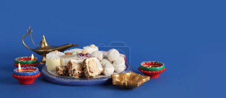 Photo for Plate with Indian treats and lamps on blue background. Divaly celebration - Royalty Free Image
