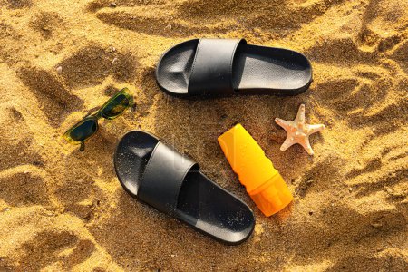 Foto de Chanclas con estilo con gafas de sol, crema de protección solar y estrellas de mar en la arena en el resort - Imagen libre de derechos