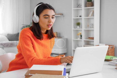 Junge Frau mit Kopfhörer lernt zu Hause online die englische Sprache