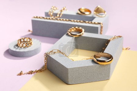 Photo for Showcase pedestals with golden rings and bracelets on color background - Royalty Free Image