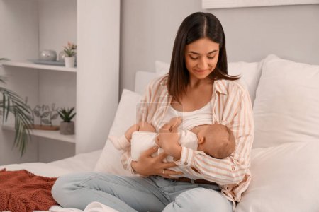 Young woman breastfeeding her baby in bedroom