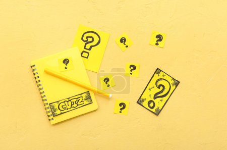 Foto de Cuaderno con tarjetas de examen y signos de interrogación sobre fondo amarillo - Imagen libre de derechos