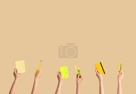 Téléchargez les photos : Hands with school supplies on beige background - en image libre de droit