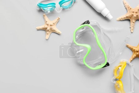 Foto de Composición con máscara de snorkel, googles, producto cosmético y estrellas de mar sobre fondo gris - Imagen libre de derechos