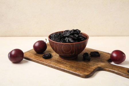Photo for Bowl with tasty prunes and ripe plums on white grunge table - Royalty Free Image