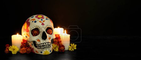 Foto de Calavera pintada para el Día de los Muertos de México, flores y velas sobre fondo oscuro con espacio para texto - Imagen libre de derechos