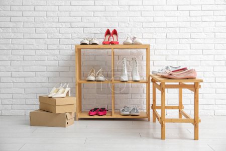 Téléchargez les photos : Unités de rayonnage en bois avec des chaussures féminines élégantes près du mur de briques légères en magasin - en image libre de droit