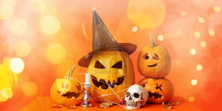 Téléchargez les photos : Jack-O-Lantern citrouilles, bougie, crâne et feuilles tombées sur fond orange - en image libre de droit