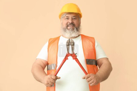 Photo for Portrait of senior man in hardhat with bolt cutter on beige background. Labor Day celebration - Royalty Free Image