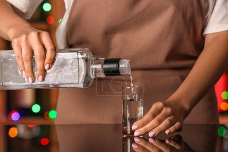 Foto de Mujer vertiendo vodka frío de botella en tiro en la mesa en el bar - Imagen libre de derechos