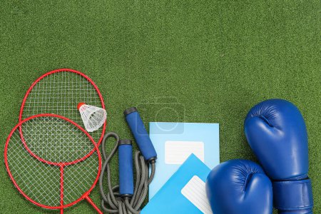 Photo for Notebooks with boxing gloves, badminton rackets and skipping rope on color background - Royalty Free Image