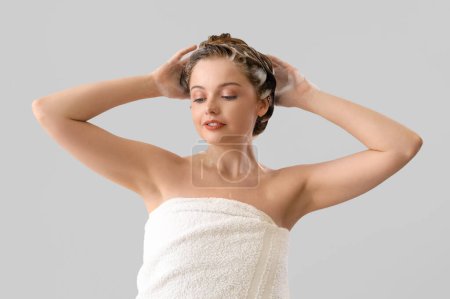 Foto de Mujer joven lavando el cabello sobre fondo claro - Imagen libre de derechos
