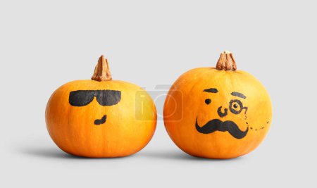 Téléchargez les photos : Funny Halloween citrouilles avec des visages dessinés sur fond gris - en image libre de droit