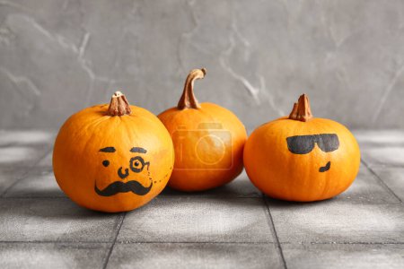 Téléchargez les photos : Funny Halloween citrouilles avec des visages dessinés sur fond de carrelage gris - en image libre de droit